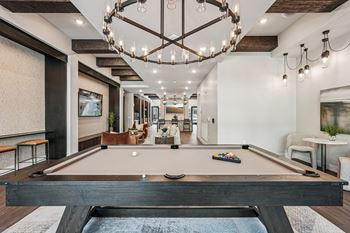 A pool table is in the middle of a room with a chandelier hanging from the ceiling